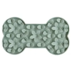 En nærbillede af en lys grøn silikone fodringsmåtte formet som et hundeknogle, udsmykket med blomster- og bladformer, designet til langsom fodring og mental stimulering af hunde.