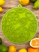Nærbillede af grøn SodaPup citrus slikkemåtte omgivet af friske citrusfrugter – designet til berigelse og stimulering af hunde.